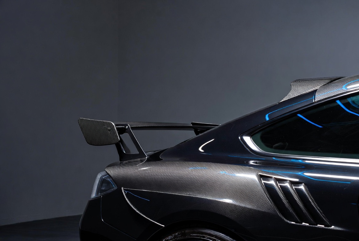 Carbon fiber GT rear wing on a dark performance coupe